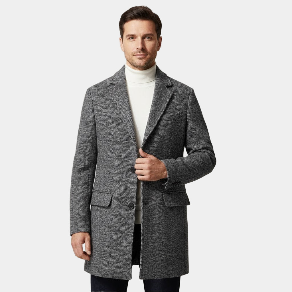 Man wearing a gray coat over a white turtleneck on a light gray background